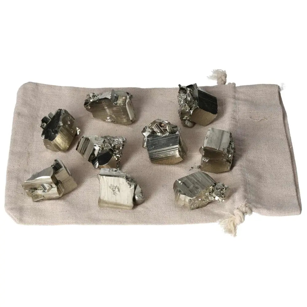Polished pyrite cubes displayed on a cloth bag, showcasing golden luster and grounding energy for space enhancement.