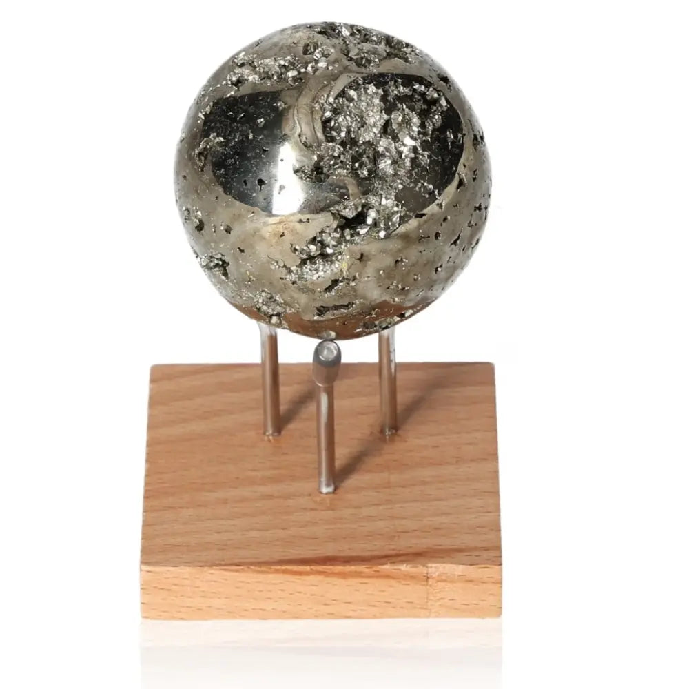Pyrite sphere with metallic luster, displayed on wooden stand, symbolizing abundance and prosperity.