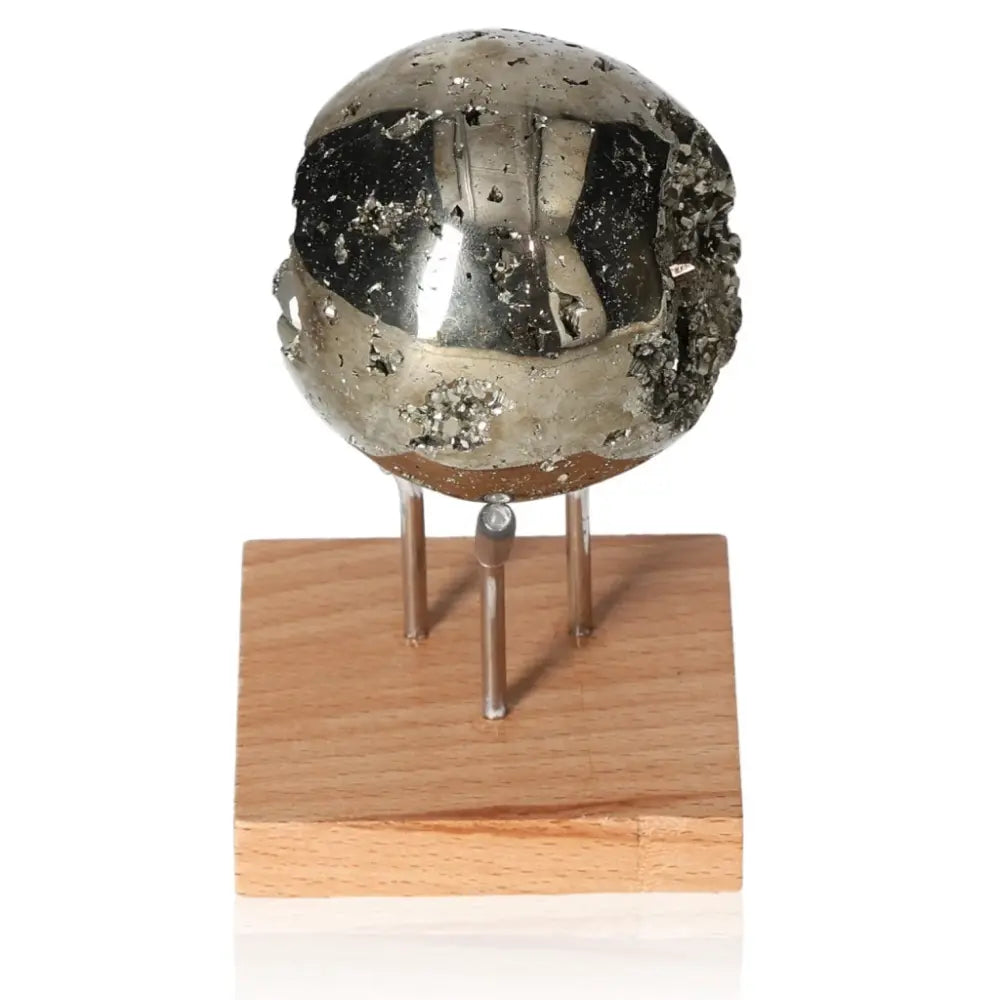 Polished pyrite sphere on wooden stand showcasing metallic luster, symbolizing abundance and prosperity.
