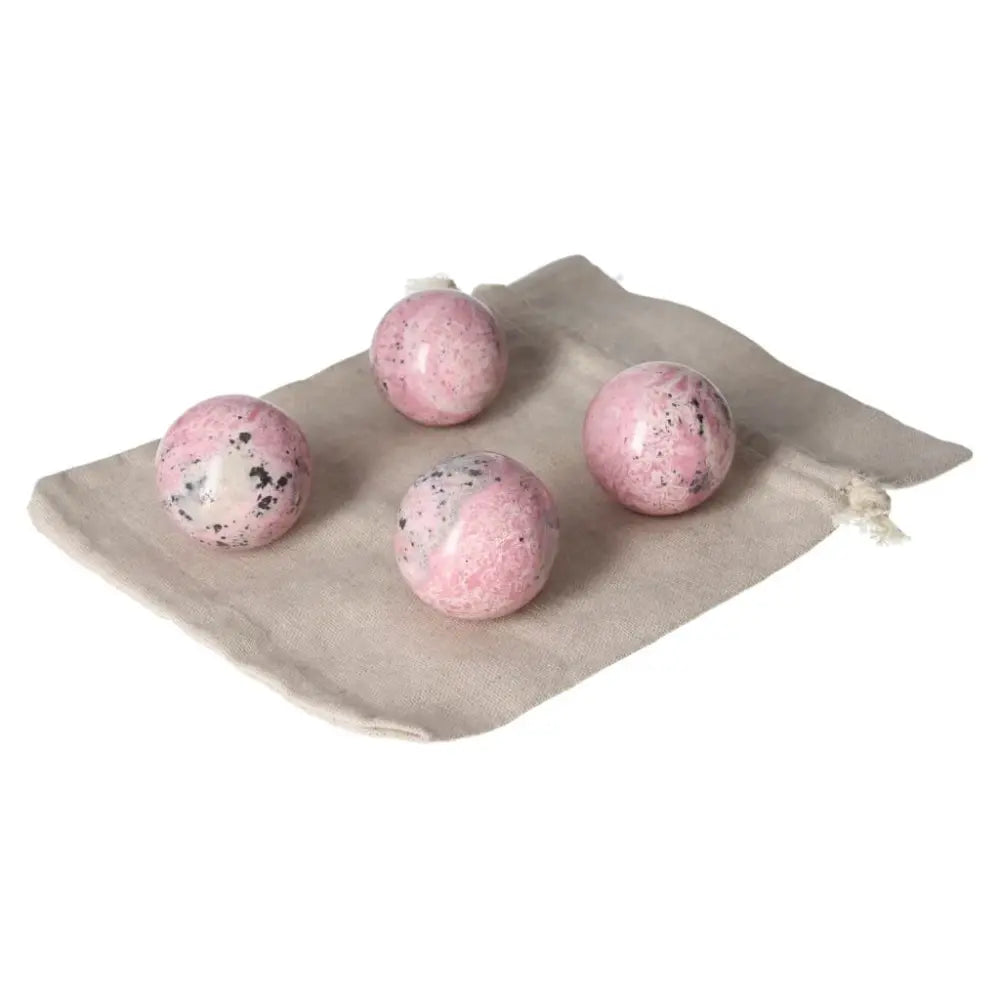 Four pink rhodonite spheres on a beige cloth, showcasing unique patterns and vibrant color for healing and energy flow.