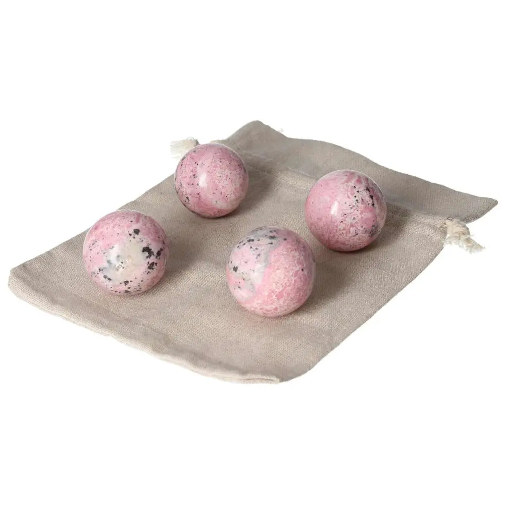 Set of four vibrant Rhodonite spheres showcasing unique patterns atop a beige cloth, known for healing and energy-clearing properties.