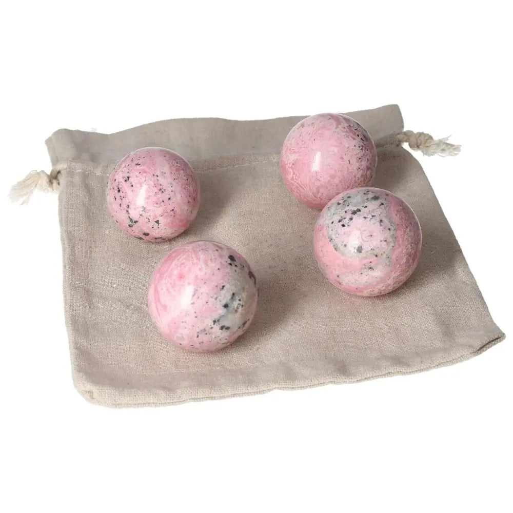 Four rhodonite spheres on a fabric pouch showcasing their vibrant colors and unique patterns for healing and positive energy flow.