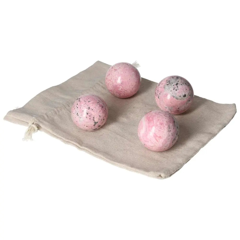 Four vibrant rhodonite spheres on a beige cloth, showcasing their unique patterns and healing properties.
