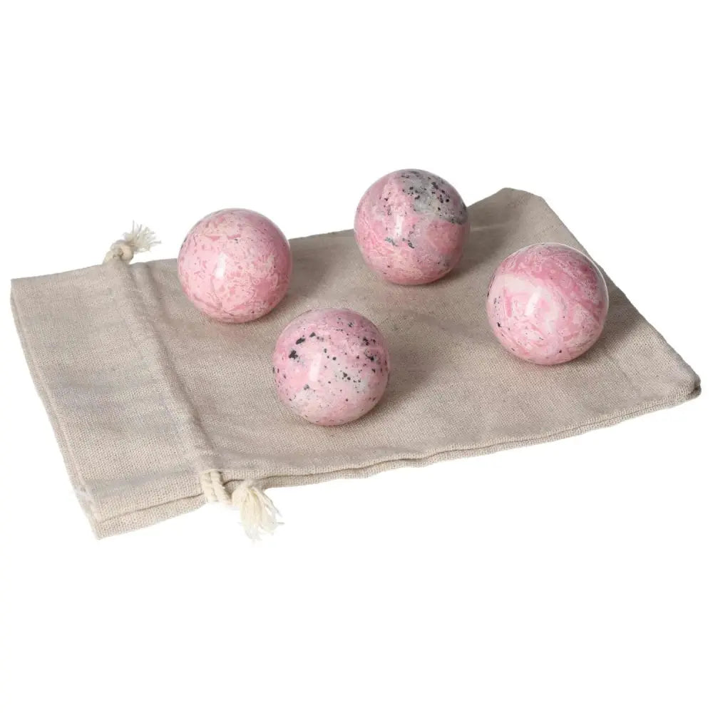 Four vibrant rhodonite spheres on a beige cloth, showcasing their unique patterns and healing properties for body, mind, and spirit.