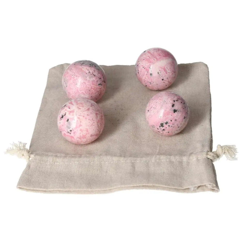 Set of four vibrant Rhodonite spheres on a pouch, known for healing energy and unique patterns.