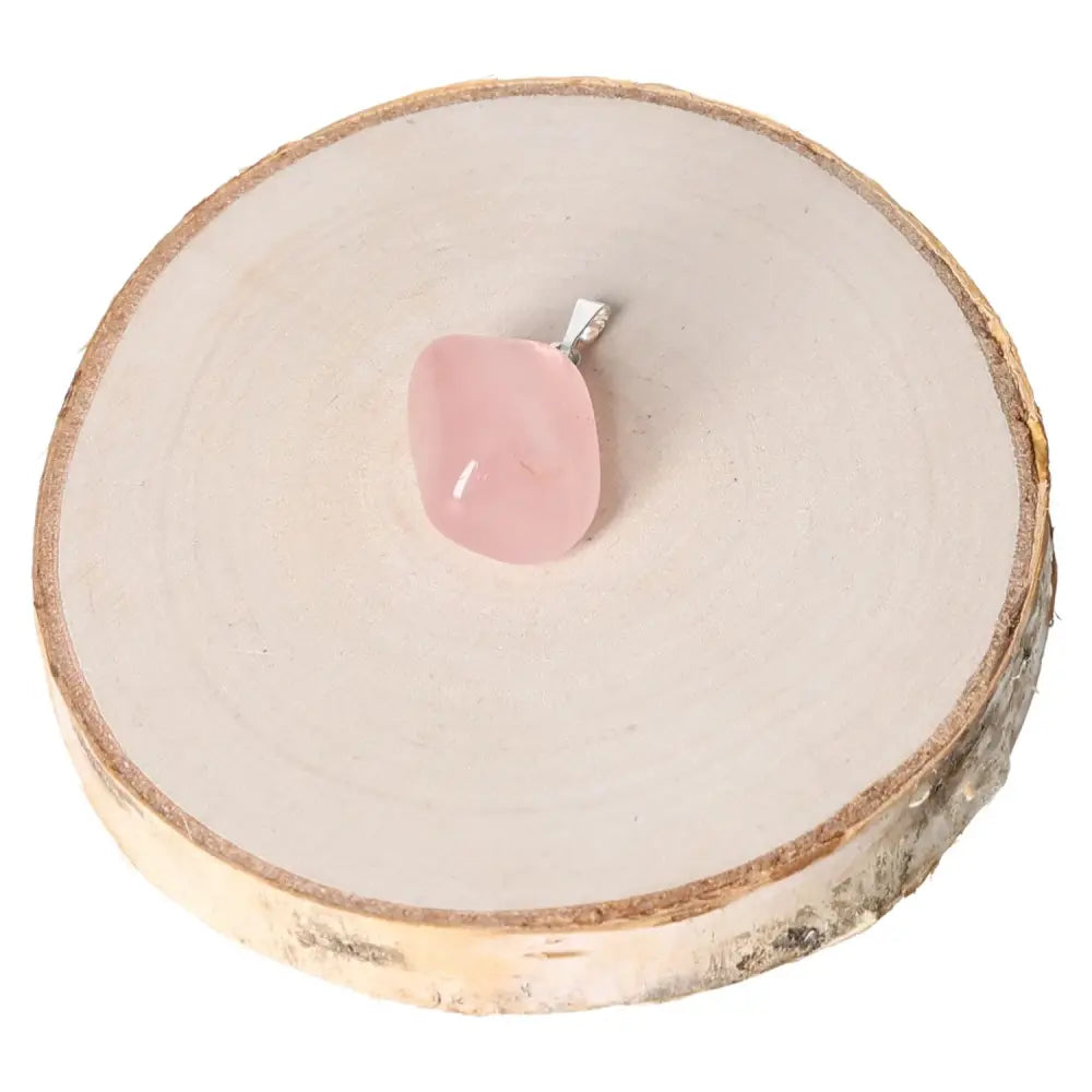 Rose Quartz Tumbled Pendant on wooden slice, showcasing its soothing pink hues and gentle energy, perfect for love and harmony.