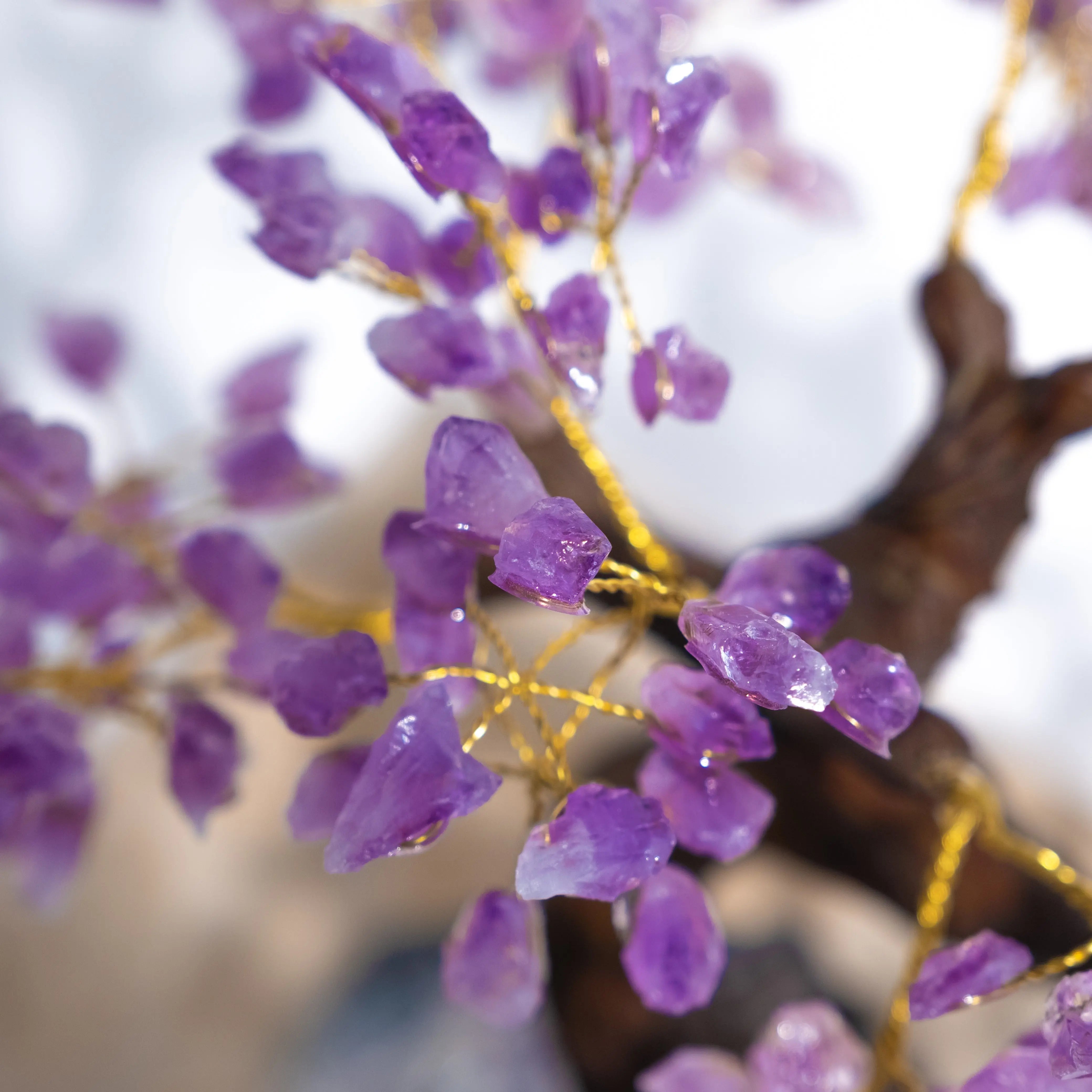 Close-up of Rough Amethyst Bonsai Tree with purple gemstones and gold wire branches, promoting calming energy and spiritual harmony.