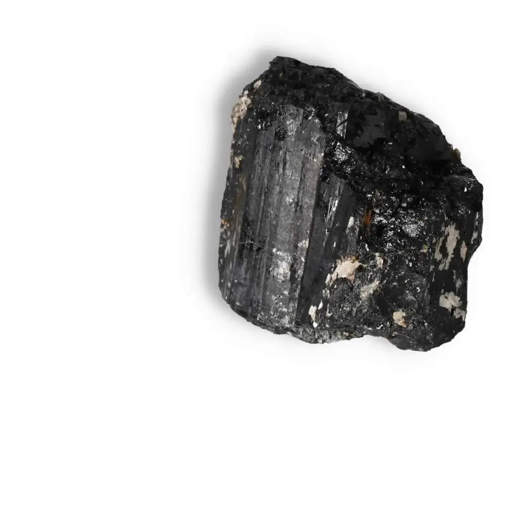 Rough Black Tourmaline Druze L stone from Sylvia Crystals, known for cleansing and transforming negative energies, on white background.