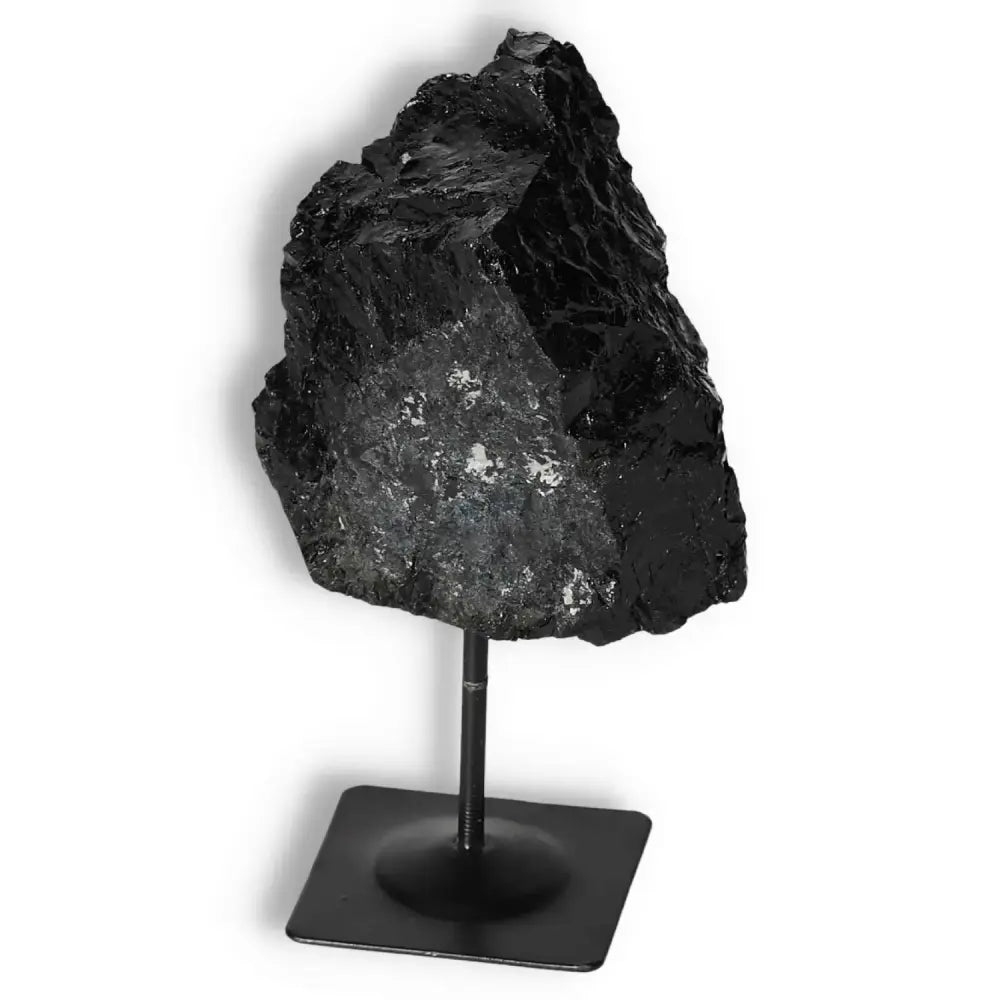 Rough black tourmaline crystal on metal stand, premium quality by Sylvia Crystals, known for energy cleansing and luxury appeal.