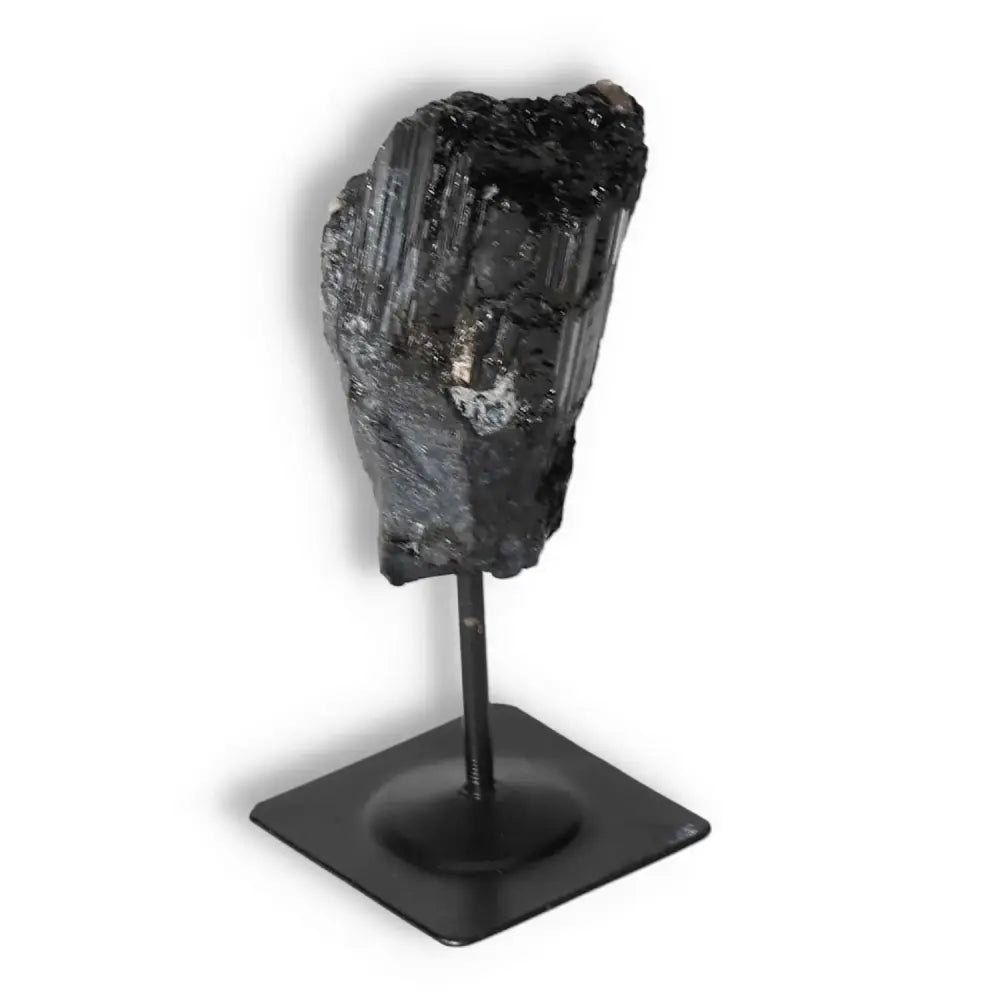 Rough Black Tourmaline on metal stand by Sylvia Crystals, known for cleansing and transformative properties, enhancing positive environments.