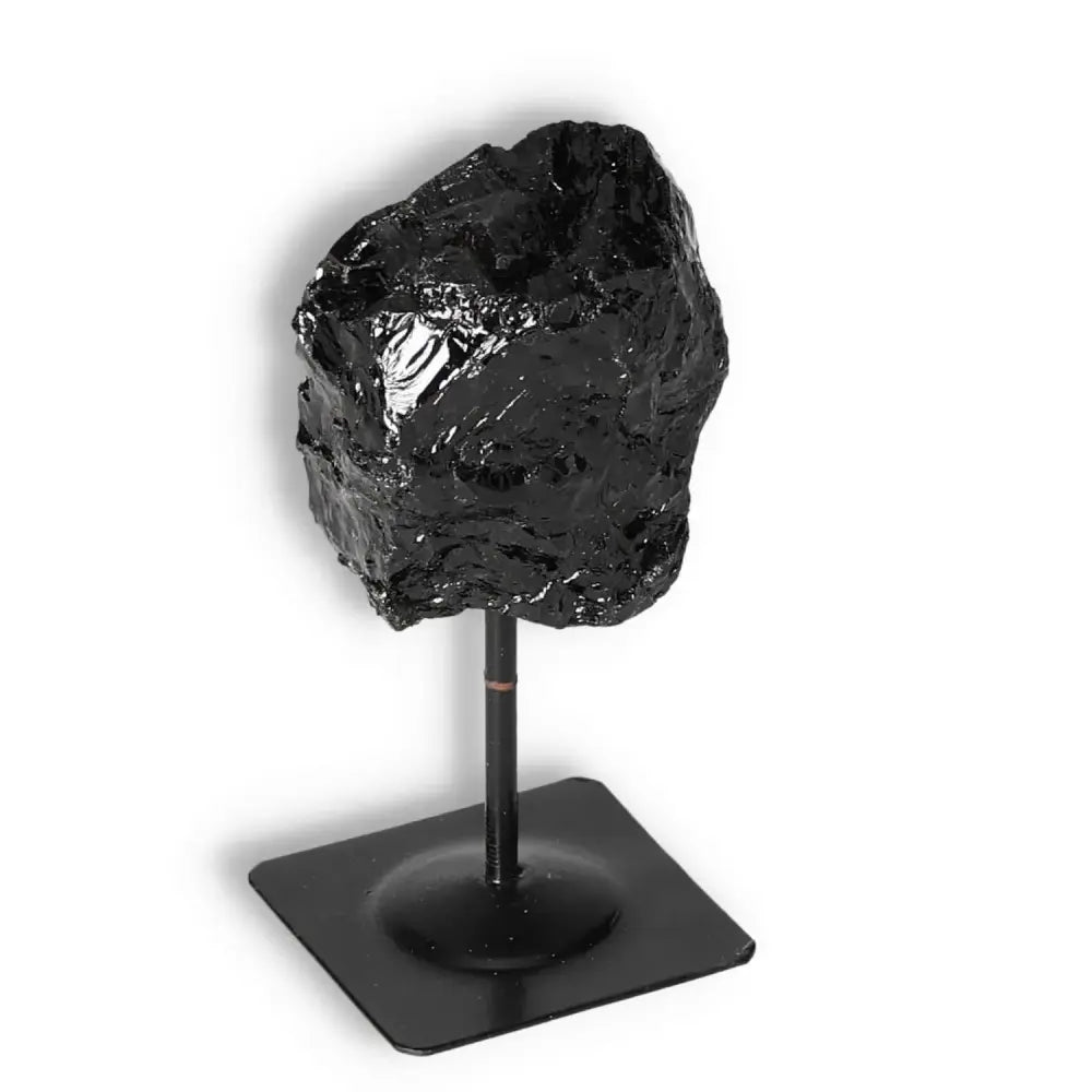 Rough Black Tourmaline gemstone on a metal stand by Sylvia Crystals, ideal for energy cleansing and spiritual enhancement.