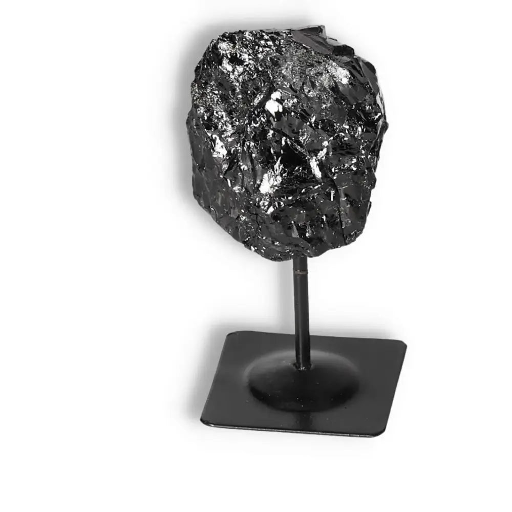 Rough Black Tourmaline gemstone on metal stand, ideal for energy cleansing and spiritual enhancement by Sylvia Crystals.