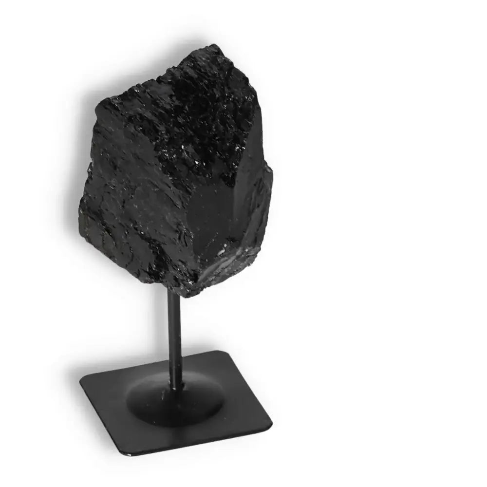 Rough black tourmaline crystal on a metal stand by Sylvia Crystals, ideal for spiritual healing and negative energy cleansing.