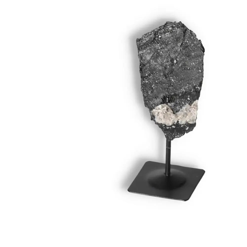 Rough Black Tourmaline with metal stand from Sylvia Crystals, ideal for cleansing and grounding, displayed on a minimalist stand.
