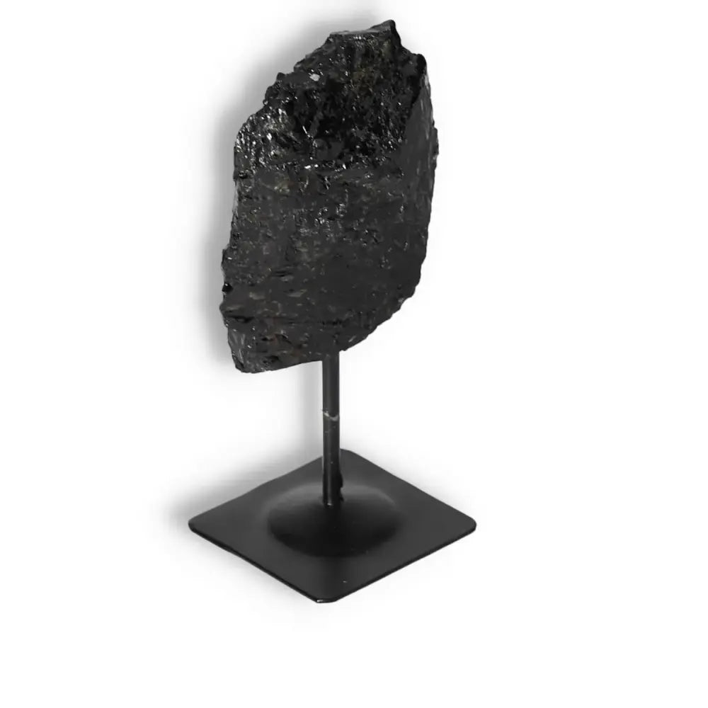 Rough Black Tourmaline on metal stand, offering powerful cleansing energy. Ideal for grounding and enhancing concentration.