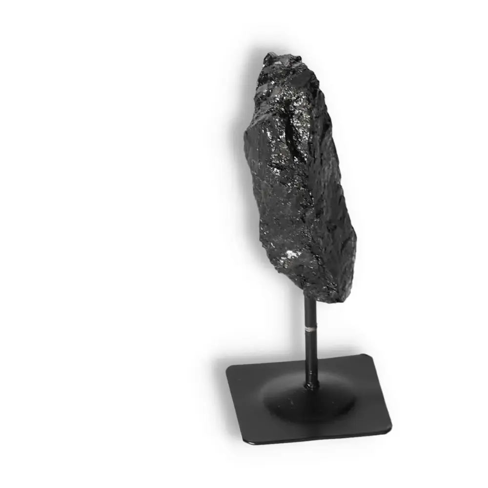 Rough Black Tourmaline on a metal stand, a powerful crystal for dispelling negative energy and enhancing concentration, by Sylvia Crystals.