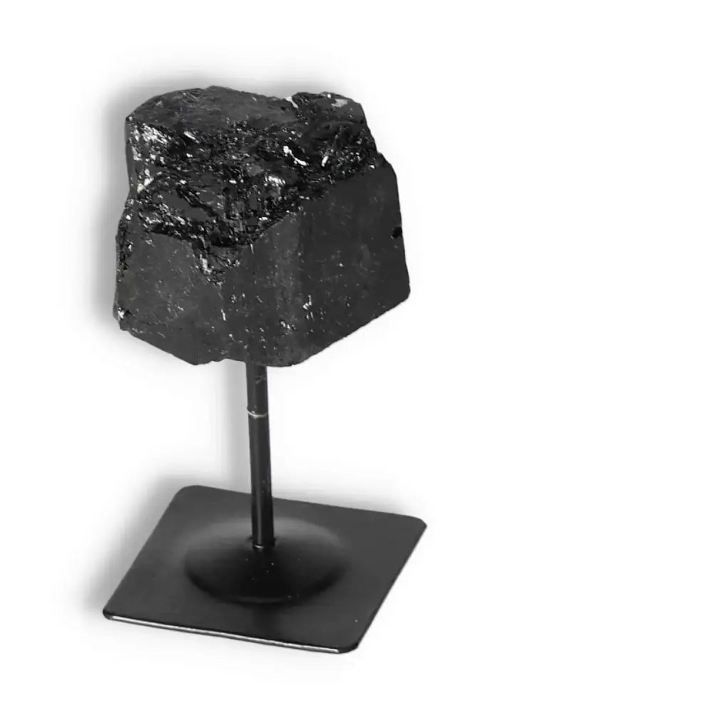 Rough Black Tourmaline on metal stand by Sylvia Crystals, known for cleansing and promoting mental balance.