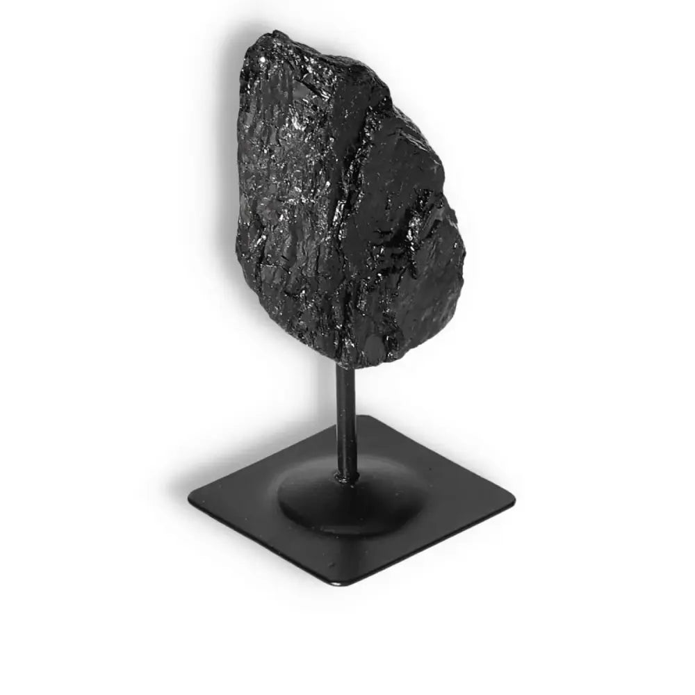 Rough black tourmaline crystal on metal stand by Sylvia Crystals, ideal for cleansing negative energies and transforming spaces.