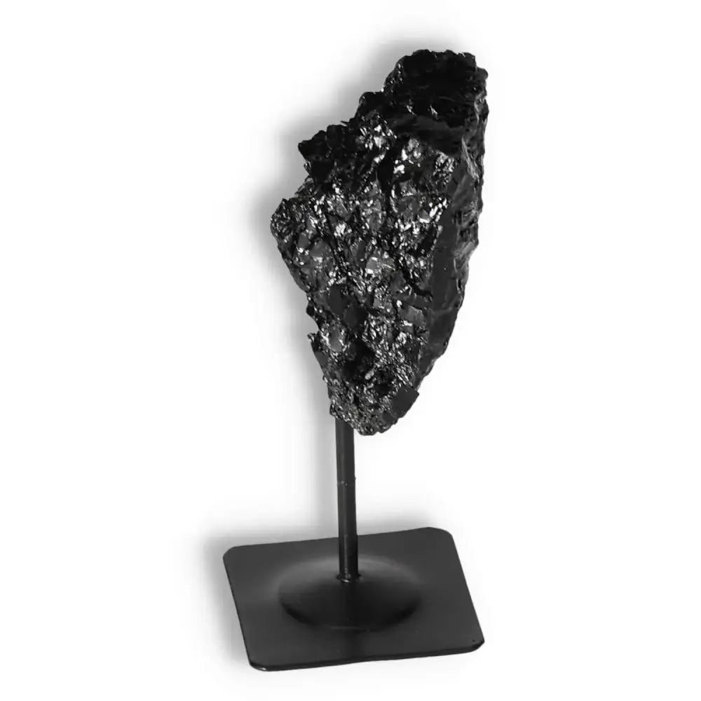 Rough Black Tourmaline on metal stand from Sylvia Crystals, a powerful tool for dissipating negative energies and enhancing decor.