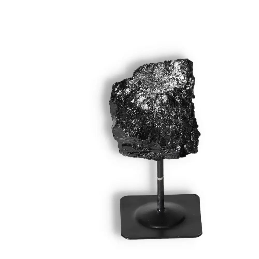 Rough Black Tourmaline on a metal stand, offering cleansing properties and energy balance, by Sylvia Crystals.