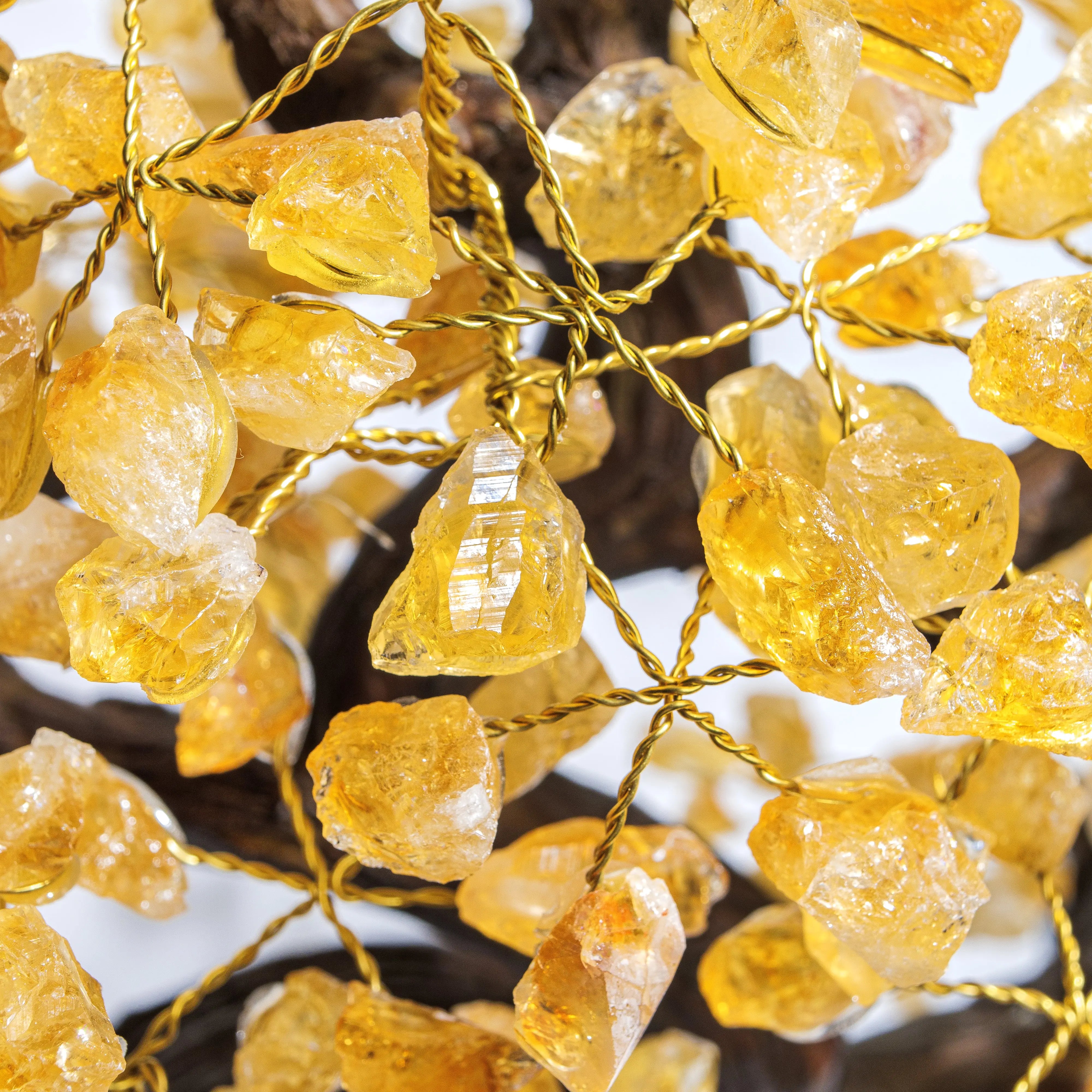 Close-up of rough citrine gemstones on a bonsai tree, symbolizing prosperity and positive energy.