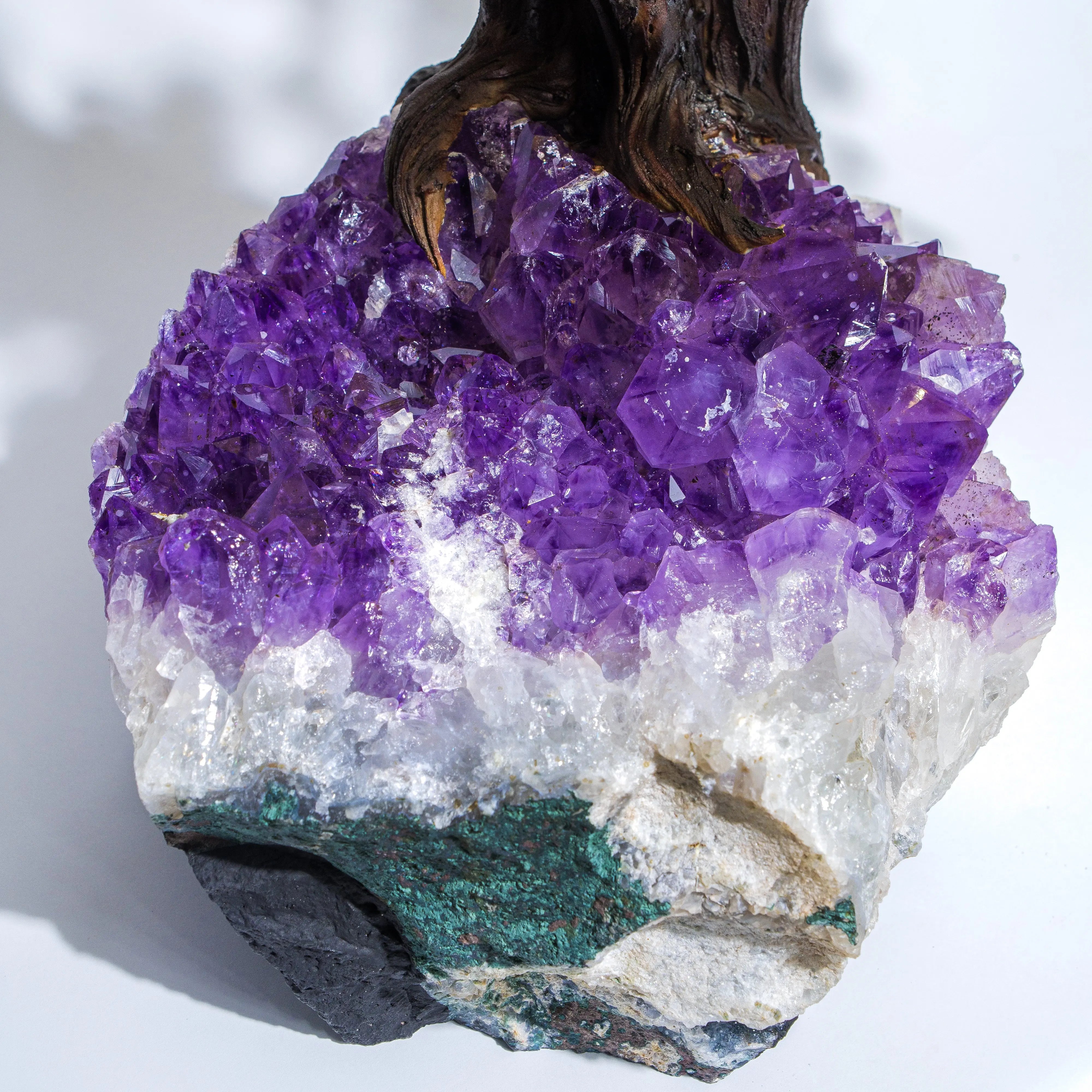 Amethyst crystal cluster with vibrant purple hues atop a rocky base, displaying beautiful natural formations and textures.