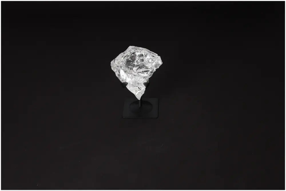 Rough Clear Quartz on metal stand against dark background, showcasing its purification and energy harmonizing properties.
