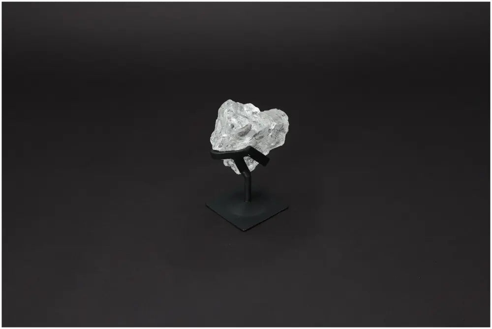 Rough Lemurian Quartz on metal stand by Sylvia Crystals, known for purification and harmonizing energy, displayed on dark background.