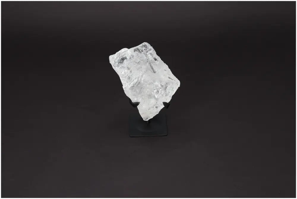 Rough Lemurian Quartz on metal stand by Sylvia Crystals, known for energy balance and harmony, displayed on a dark background.