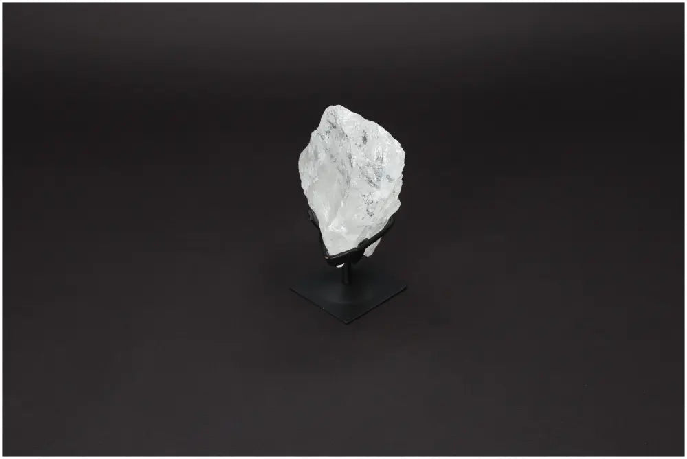 Rough Lemurian Quartz on metal stand against dark background, offered by Sylvia Crystals for energy balance and purification.