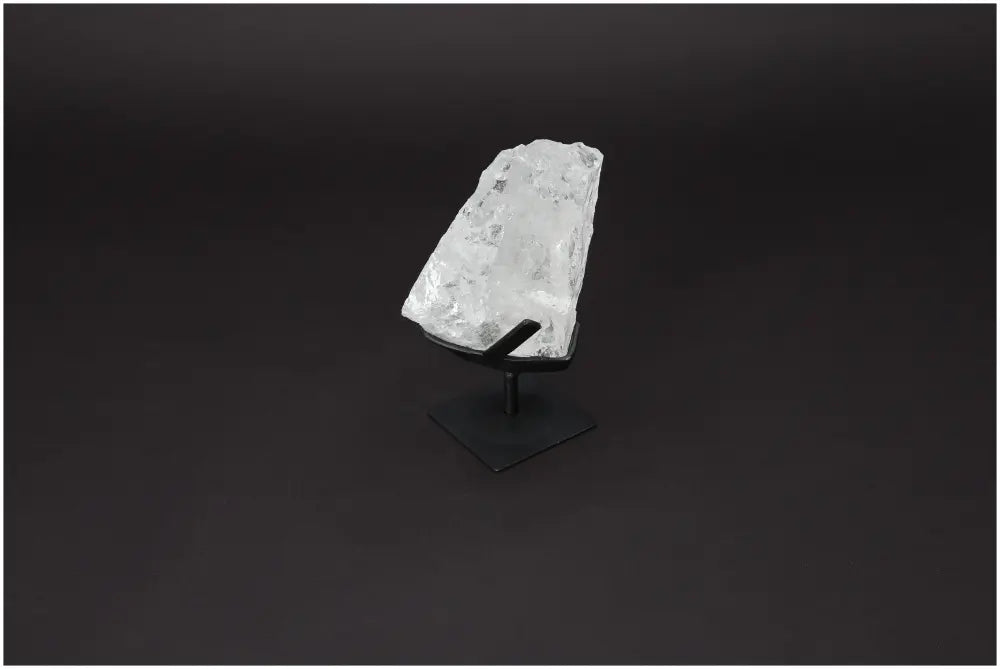 Rough Lemurian Quartz on elegant metal stand, showcasing clear quartz's purifying energy for body and mind harmony by Sylvia Crystals.