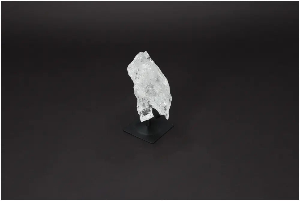 Rough Lemurian Clear Quartz on metal stand by Sylvia Crystals, known for energy harmonization and purification properties.