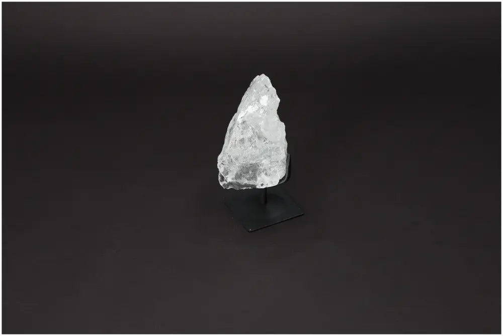 Rough Lemurian Quartz on a metal stand, designed by Sylvia Crystals, against a dark background. Perfect for decor and energy purification.