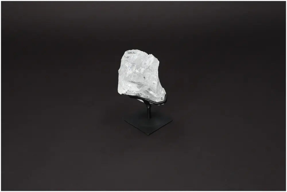 Rough Clear Quartz on Metal Stand by Sylvia Crystals, showcasing natural elegance and purification properties against black background.