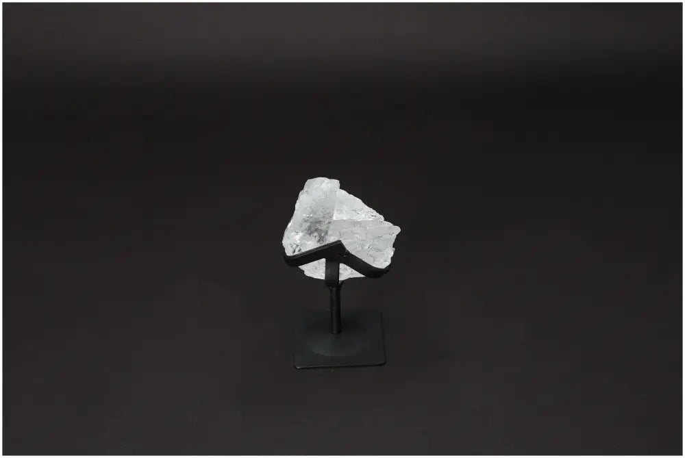 Rough Lemurian Quartz on metal stand against dark background, premium Sylvia Crystals product for energy balance and purification.