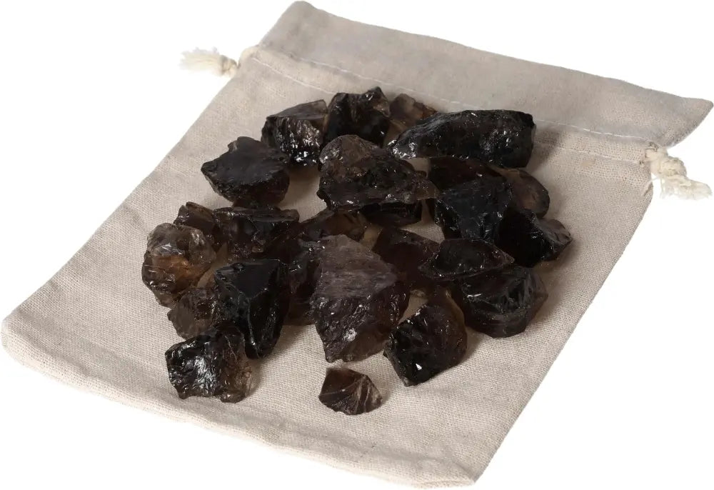 Rough Smoky Quartz stones on a beige cloth bag by Sylvia Crystals, ideal for enhancing mental clarity and grounding.