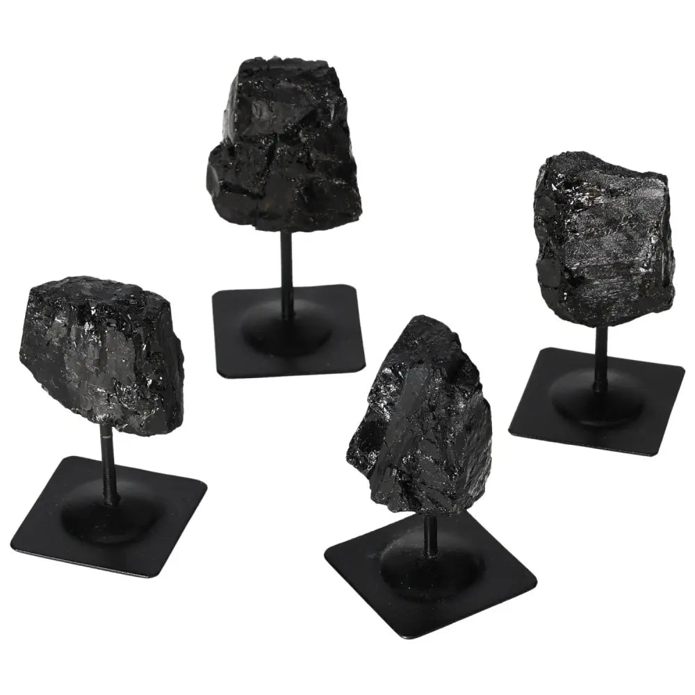 Rough tourmaline stones with metal stands, featuring deep blacks, showcasing natural beauty and artistic design by Sylvia Crystals.