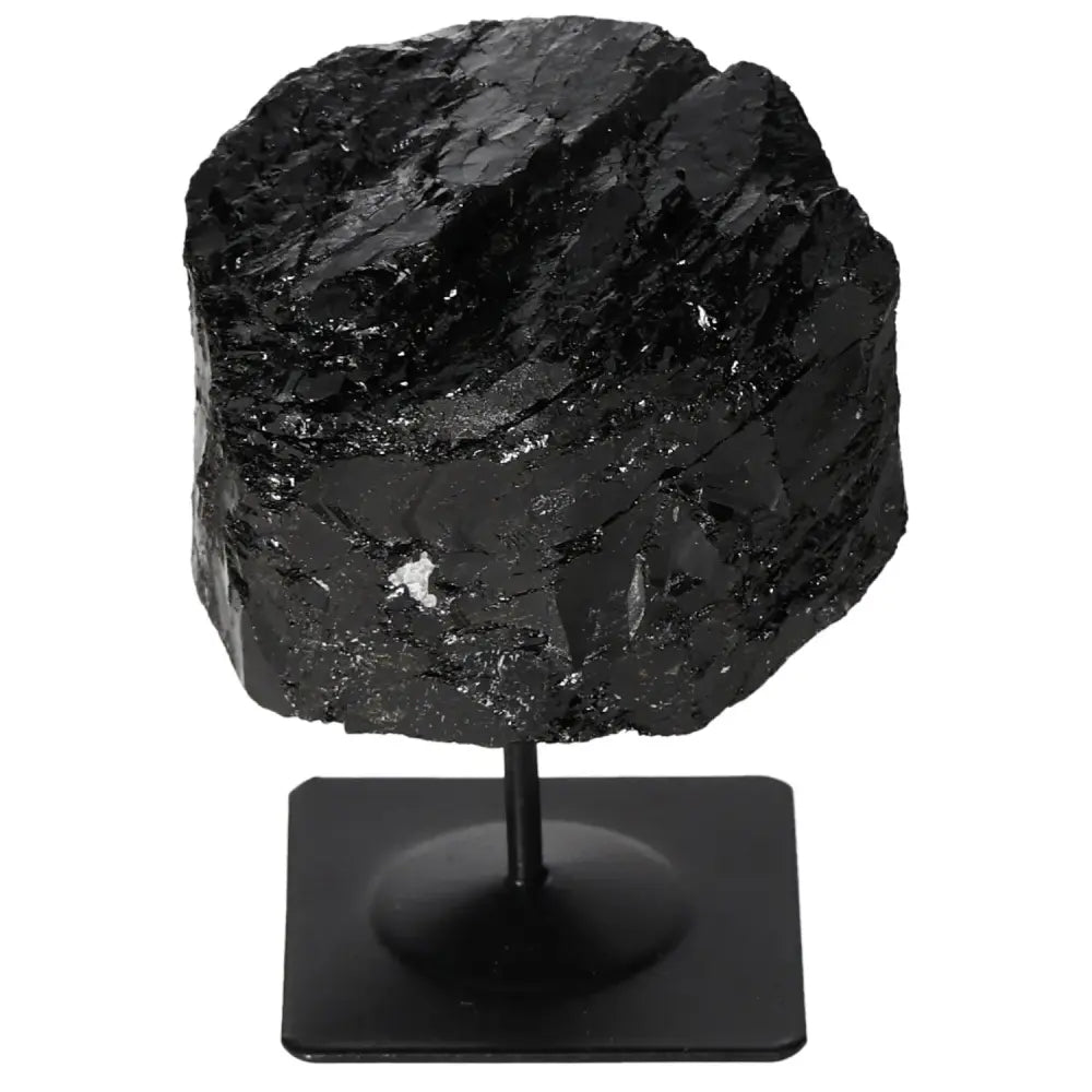 Rough black tourmaline crystal on a sleek metal stand, showcasing deep natural textures and hues, by Sylvia Crystals.