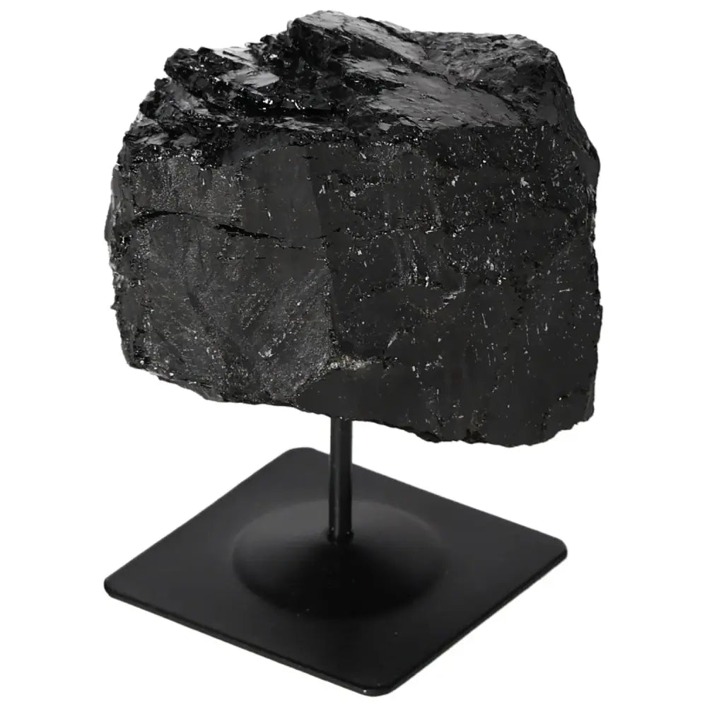 Rough black tourmaline crystal on a sleek metal stand, showcasing natural raw texture and vibrant hues, from Sylvia Crystals.