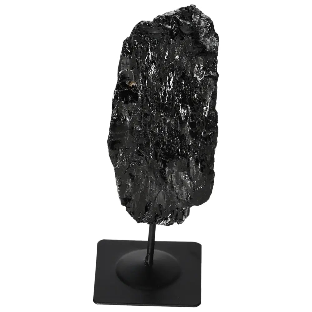 Rough black tourmaline gemstone on metal stand showcasing natural beauty by Sylvia Crystals.