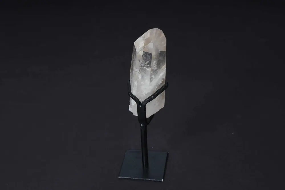 Semi-polished clear quartz point on stand, ideal for amplifying energy and enhancing clarity in meditation and energy work.