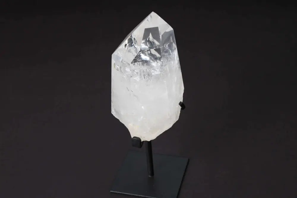 Semi Polished Clear Quartz Point with Stand on black background, enhancing energy and clarity, ideal for meditation and manifestation.