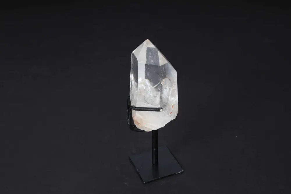 Semi polished clear quartz point on elegant stand, ideal for amplifying energy and clarity in meditation or home decor.