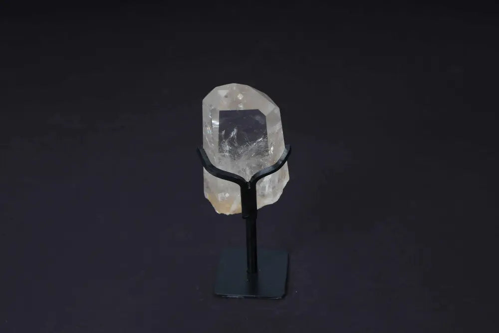 Semi polished clear quartz point on stand, ideal for meditation and enhancing clarity, showcased against a dark background.
