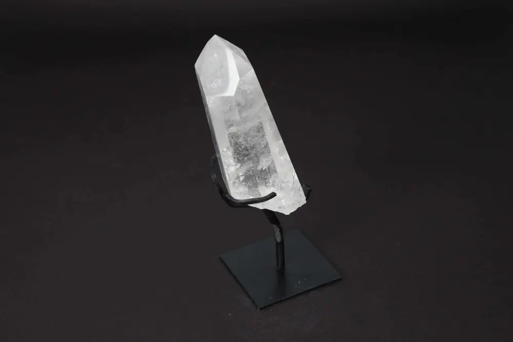 Semi-polished clear quartz point on a stand, ideal for meditation and energy work, enhances clarity and focus in any space.