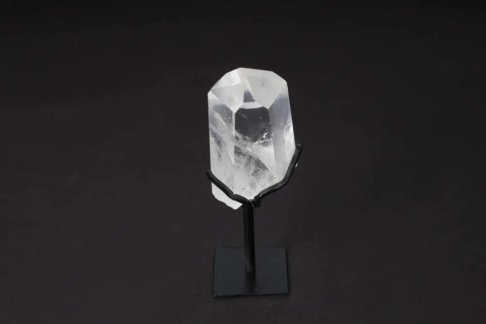 Semi-polished clear quartz point on a modern stand, ideal for meditation and energy amplification, displayed against a dark background.