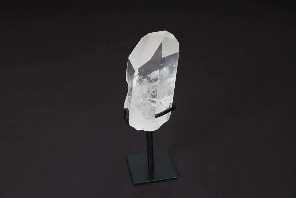 Semi Polished Clear Quartz Point with Stand on black background, ideal for amplifying energy and meditation, elegant centerpiece.