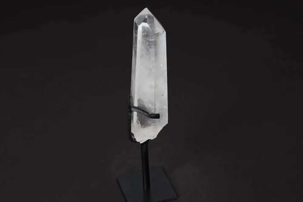 Semi polished clear quartz point on a stand, known for amplifying energy and clarity, ideal for meditation and energy work.