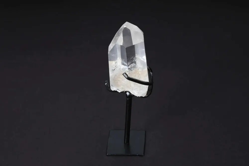 Semi polished clear quartz point on a modern stand for energy amplification and clarity, ideal for meditation and space decor.