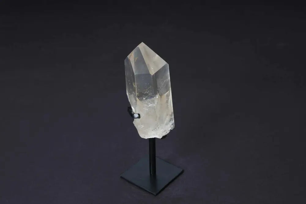 Semi-polished smoky quartz crystal point on stand, highlighting grounding elegance and protective energy